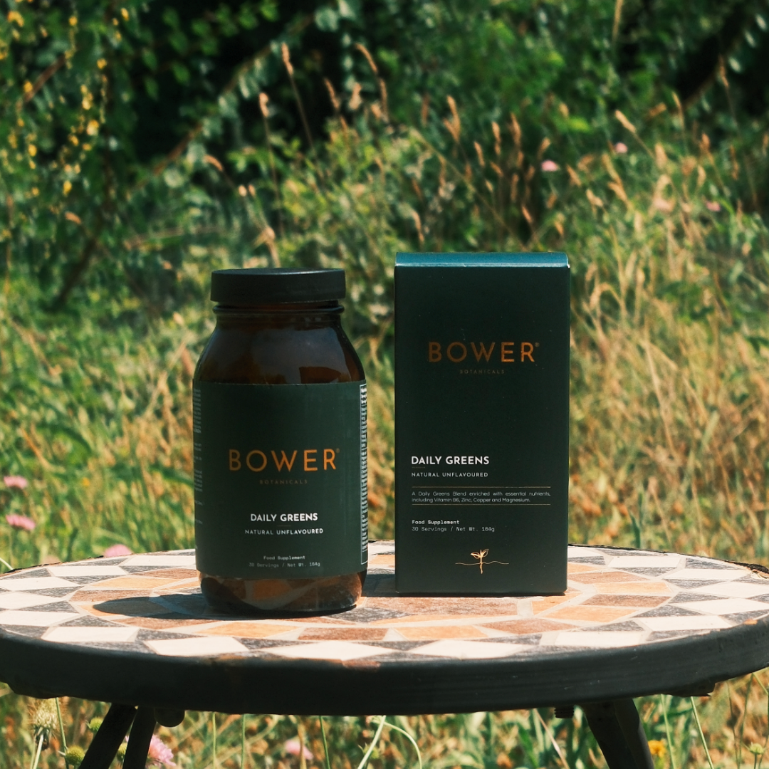 Bower Botanicals Daily Greens Powder box and jar displayed on a stone surface
